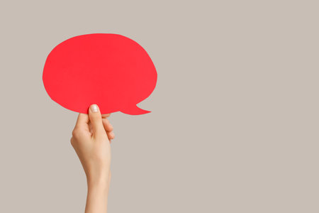 Female hand with speech bubble on gray backgroundの写真素材