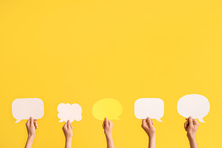 Different hands with speech bubbles on yellow backgroundの写真素材