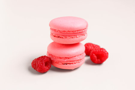 Tasty sweet macaroons and raspberries on pink backgroundの写真素材