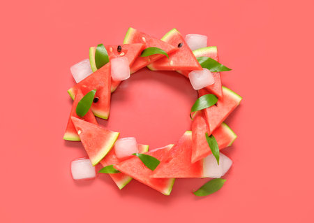 Frame made of fresh watermelon with leaves and ice cubes on red backgroundの写真素材