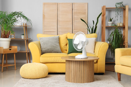 Interior of living room with yellow sofa and electric fan on wooden coffee tableの写真素材
