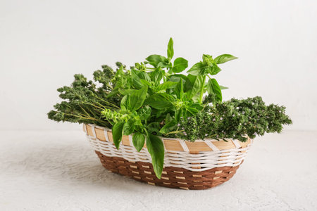 Wicker basket with fresh herbs on light backgroundの写真素材