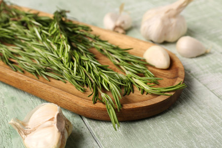 Board with fresh rosemary and garlic on color wooden background, closeupの写真素材