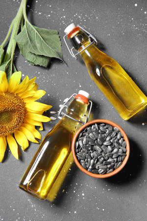 Bottles of sunflower oil and bowl with seeds on black backgroundの写真素材