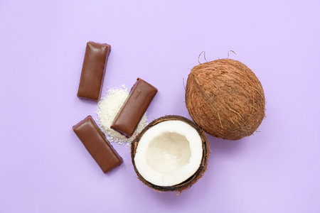 Tasty chocolate covered candies and coconuts on lilac backgroundの写真素材