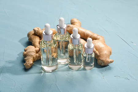 Bottles of ginger cosmetic oil on blue background