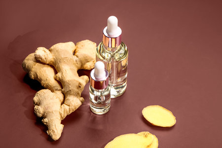 Bottles of ginger cosmetic oil on brown backgroundの写真素材