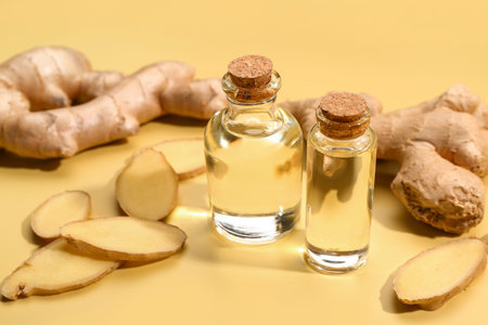 Bottles of ginger cosmetic oil on yellow backgroundの写真素材