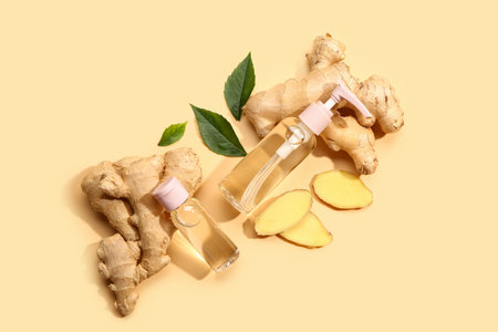 Bottles of ginger cosmetic oil and leaves on yellow backgroundの写真素材