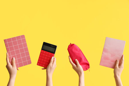 Female hands with school supplies on yellow backgroundの写真素材