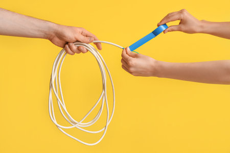 Electrician hands insulating wire on yellow backgroundの写真素材