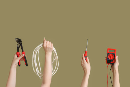 Electrician hands with tools and wire on green backgroundの写真素材