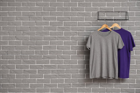 Stylish t-shirts hanging on gray brick wallの写真素材