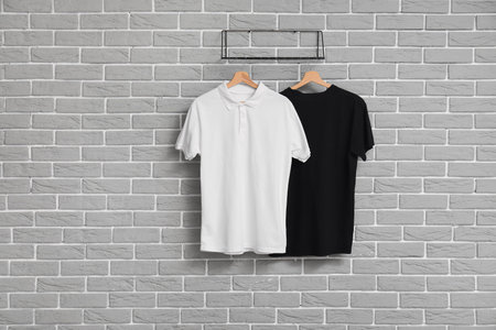 Stylish t-shirts hanging on gray brick wall