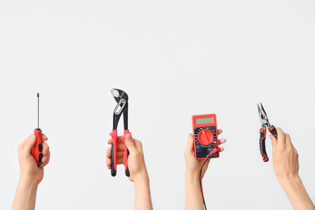 Electrician hands with tools on gray background