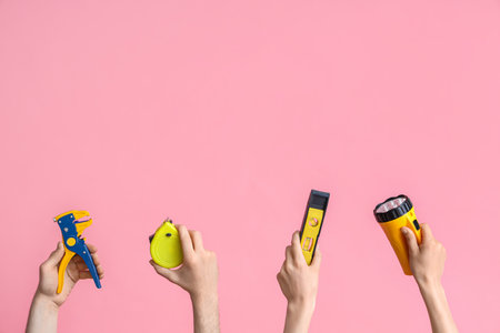 Electrician hands with tools on pink backgroundの写真素材
