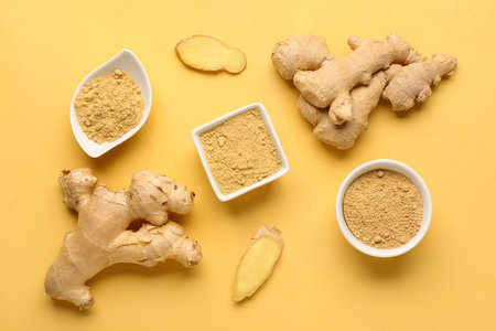 Fresh ginger roots and bowls with dried powder on yellow backgroundの写真素材