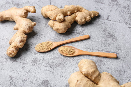 Fresh ginger roots and wooden spoons with dried powder on blue backgroundの写真素材