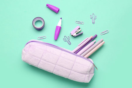 Pencil case with different stationery on turquoise background
