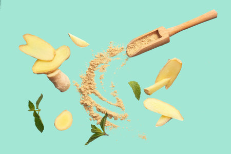 Slices of fresh ginger root and wooden scoop with dried powder on turquoise background