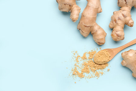 Fresh ginger roots and wooden spoon with dried powder on blue backgroundの写真素材