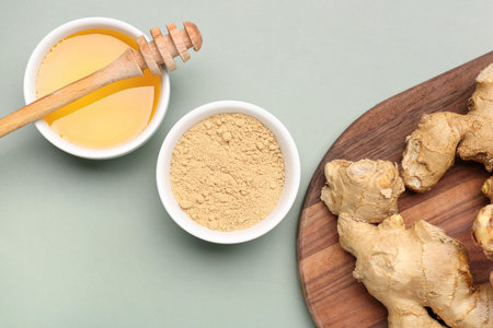 Fresh ginger root and bowl with dried powder on gray background