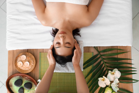 Pretty young Asian woman having facial massage in spa salon, top viewの写真素材