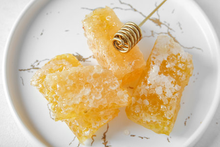Plate with fresh honeycombs and dipper on light background, closeupの写真素材