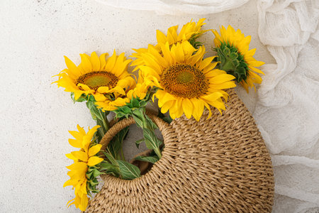Stylish straw bag with beautiful sunflowers on white backgroundの写真素材