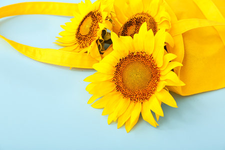 Stylish eco bag with beautiful sunflowers on blue backgroundの写真素材