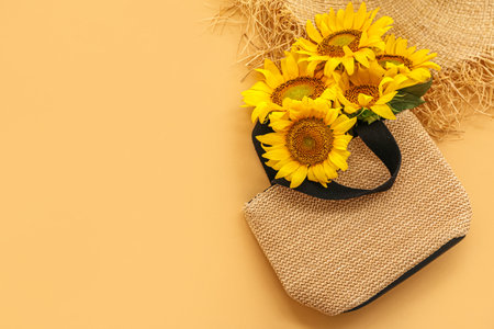 Stylish straw bag with beautiful sunflowers on orange backgroundの写真素材