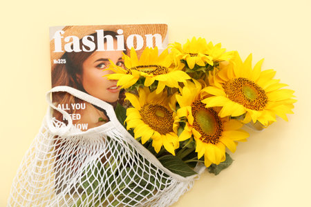 String bag with beautiful sunflowers and magazine on yellow backgroundの写真素材