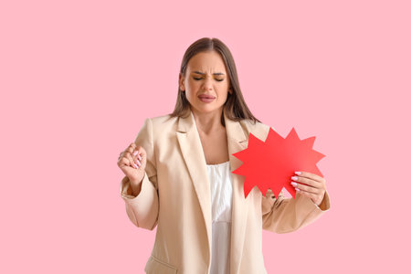 Beautiful angry young woman with speech bubble on pink backgroundの写真素材
