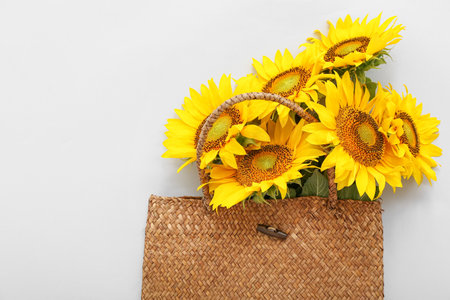 Stylish straw bag with beautiful sunflowers on gray backgroundの写真素材