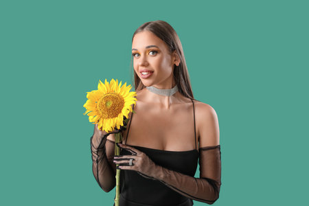 Elegant happy young woman with beautiful sunflower on green backgroundの写真素材