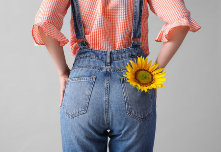 Young woman with beautiful sunflower on gray background, back viewの写真素材