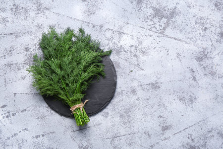 Slate board with bunch of fresh dill on gray backgroundの写真素材