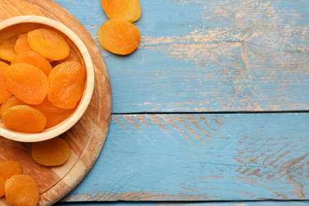 Bowl with tasty dried apricots on blue wooden backgroundの写真素材