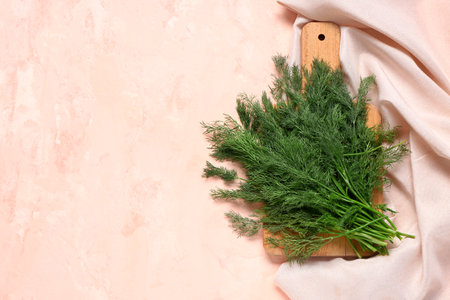 Wooden board with fresh dill on pink backgroundの写真素材