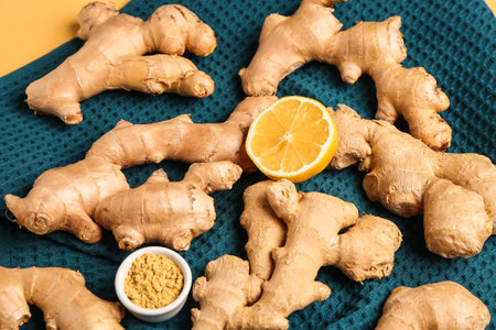 Fresh ginger roots, half of lemon and bowl with dried powder on yellow background, closeupの写真素材