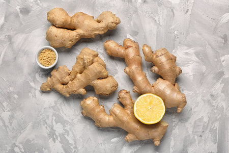 Fresh ginger roots, half of lemon and bowl with dried powder on grunge backgroundの写真素材