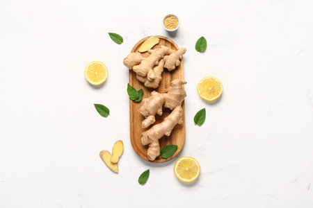 Wooden board with fresh ginger roots and slices of lemon on white backgroundの写真素材
