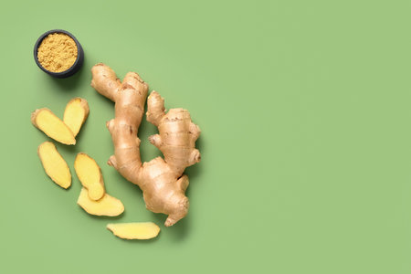 Fresh ginger root and bowl of dried powder on green backgroundの写真素材