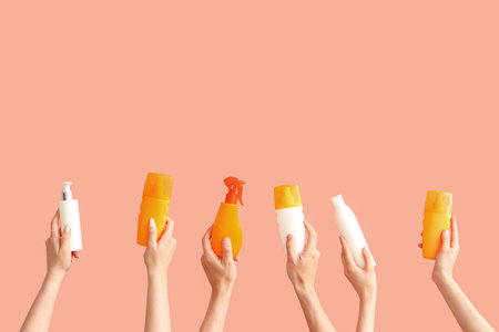 Female hands with bottles of sunscreen cream on color backgroundの写真素材