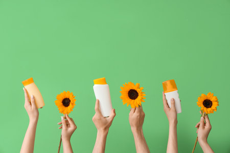 Female hands with bottles of sunscreen cream and sunflowers on green backgroundの写真素材