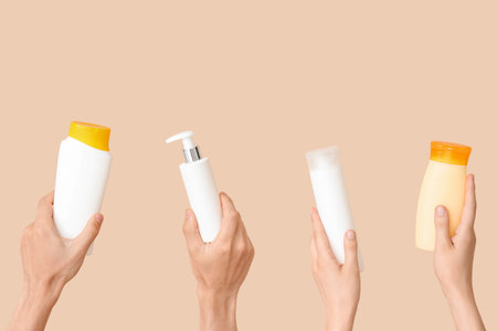 Female hands with bottles of sunscreen cream on beige backgroundの写真素材