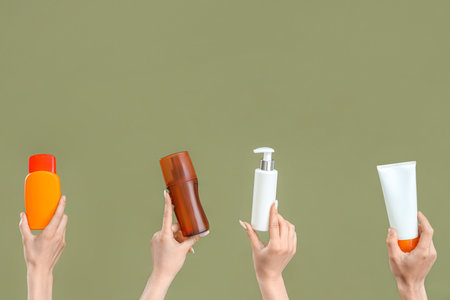 Female hands with bottles of sunscreen cream on green backgroundの写真素材