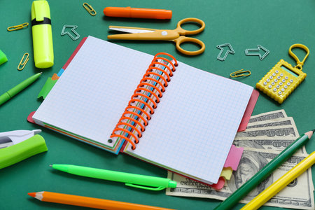 Blank notebook with money and different stationery on green backgroundの写真素材
