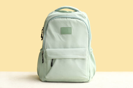 Green school backpack on white grunge table near yellow wallの写真素材