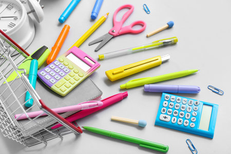 Alarm clock with shopping basket full of different stationery on gray backgroundの写真素材